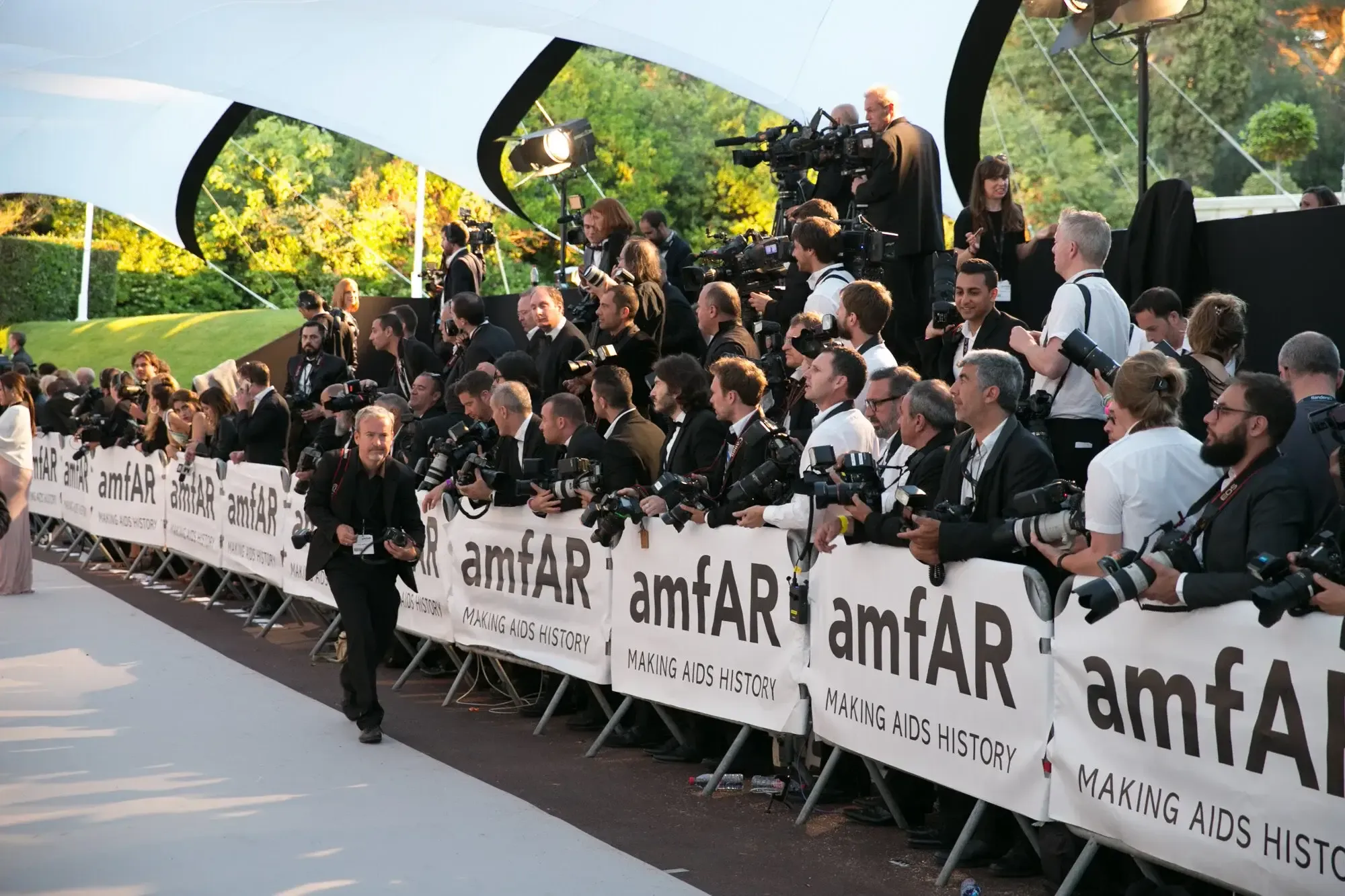 Packed amfAR press pit of photographers behind branded barriers at a Cannes gala