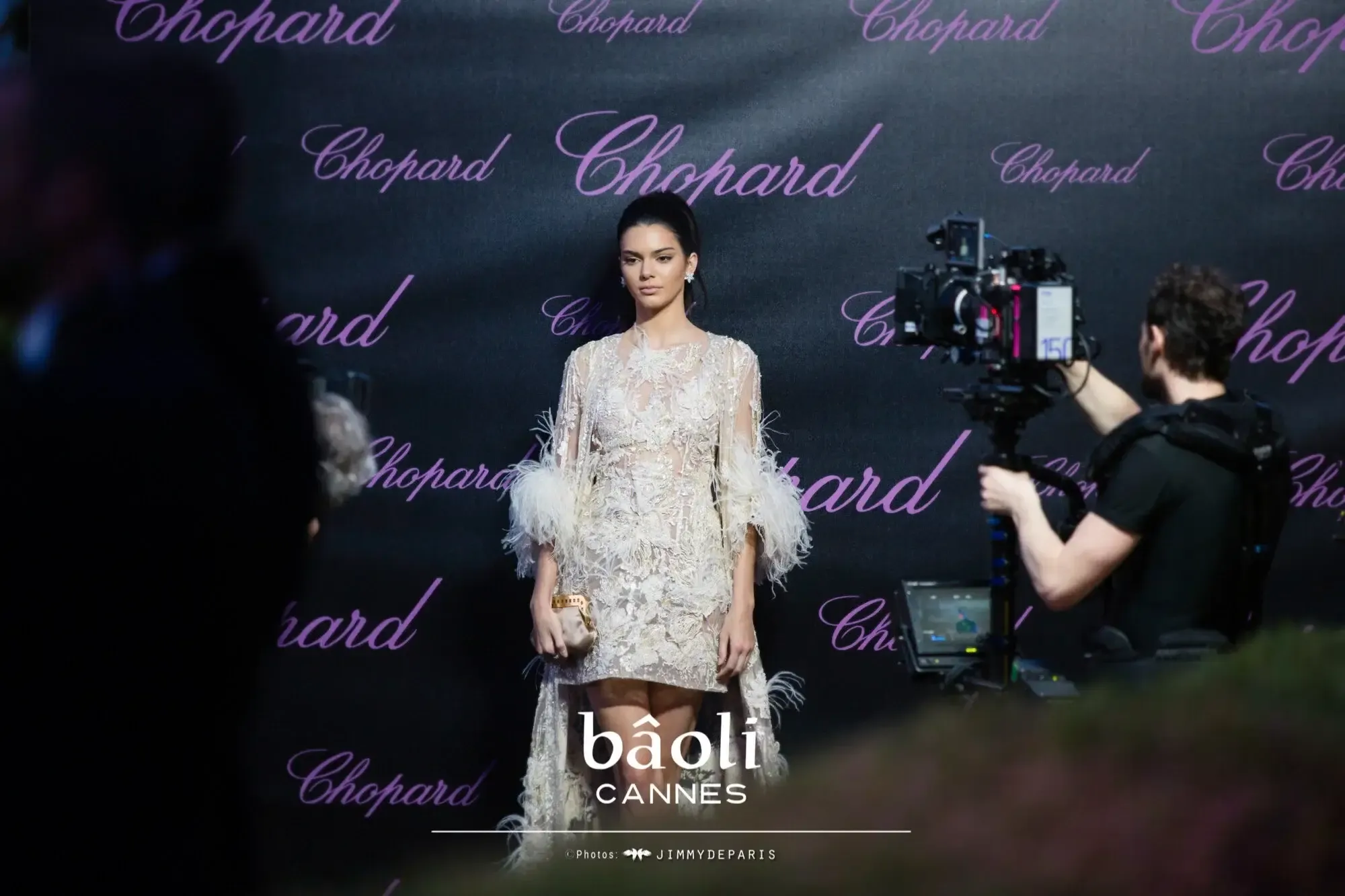 Kendall Jenner in a cream lace feathered dress on a Chopard backdrop at Bâoli Cannes