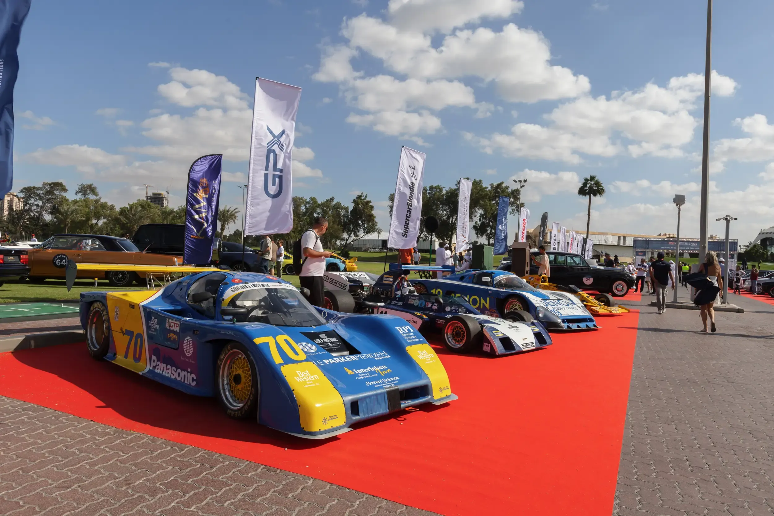 Vintage Gulf Historic race cars on a red carpet at a GPX / Supercar Blondie outdoor display
