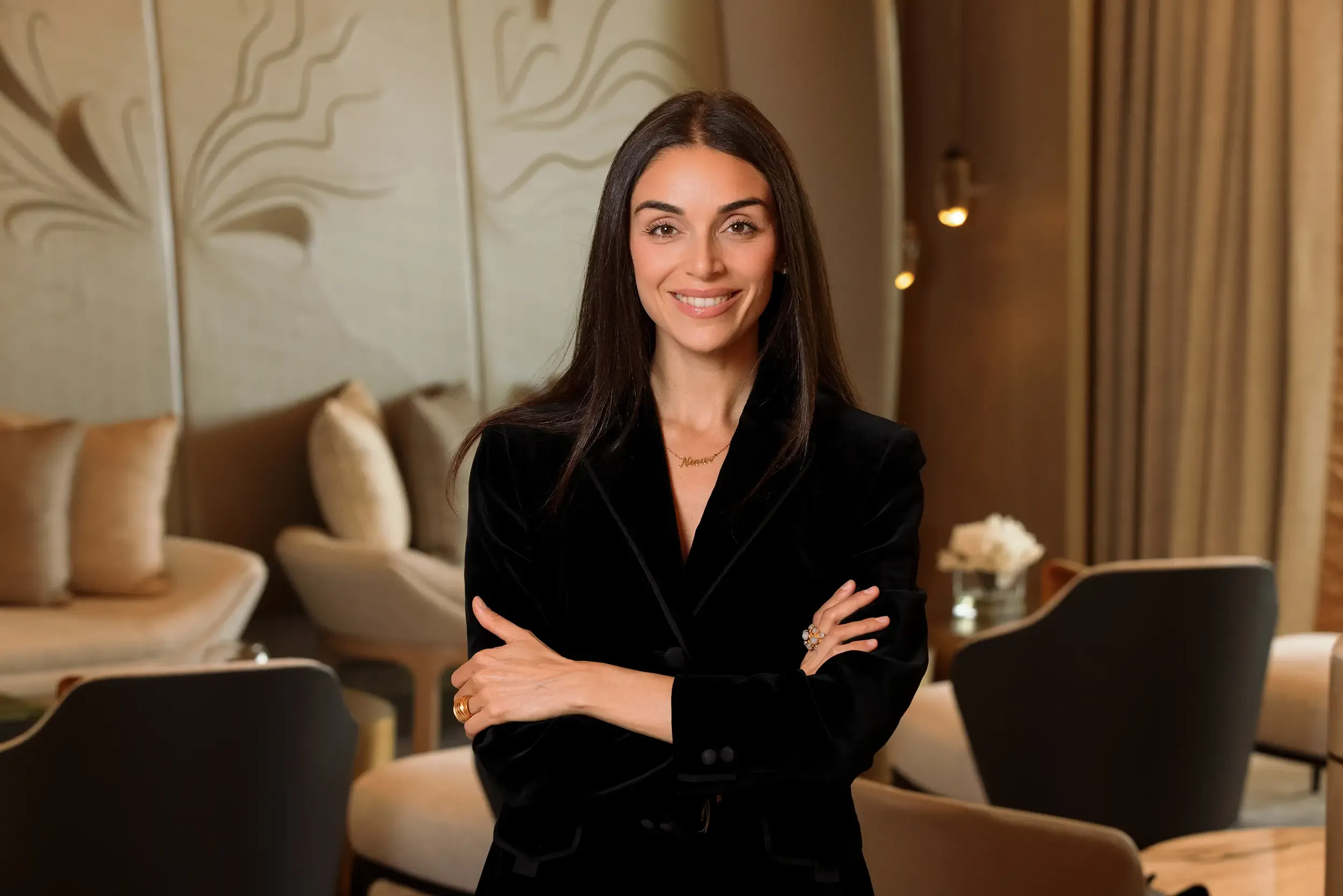 Executive woman in black velvet blazer with arms crossed in a luxury Four Seasons residence lobby