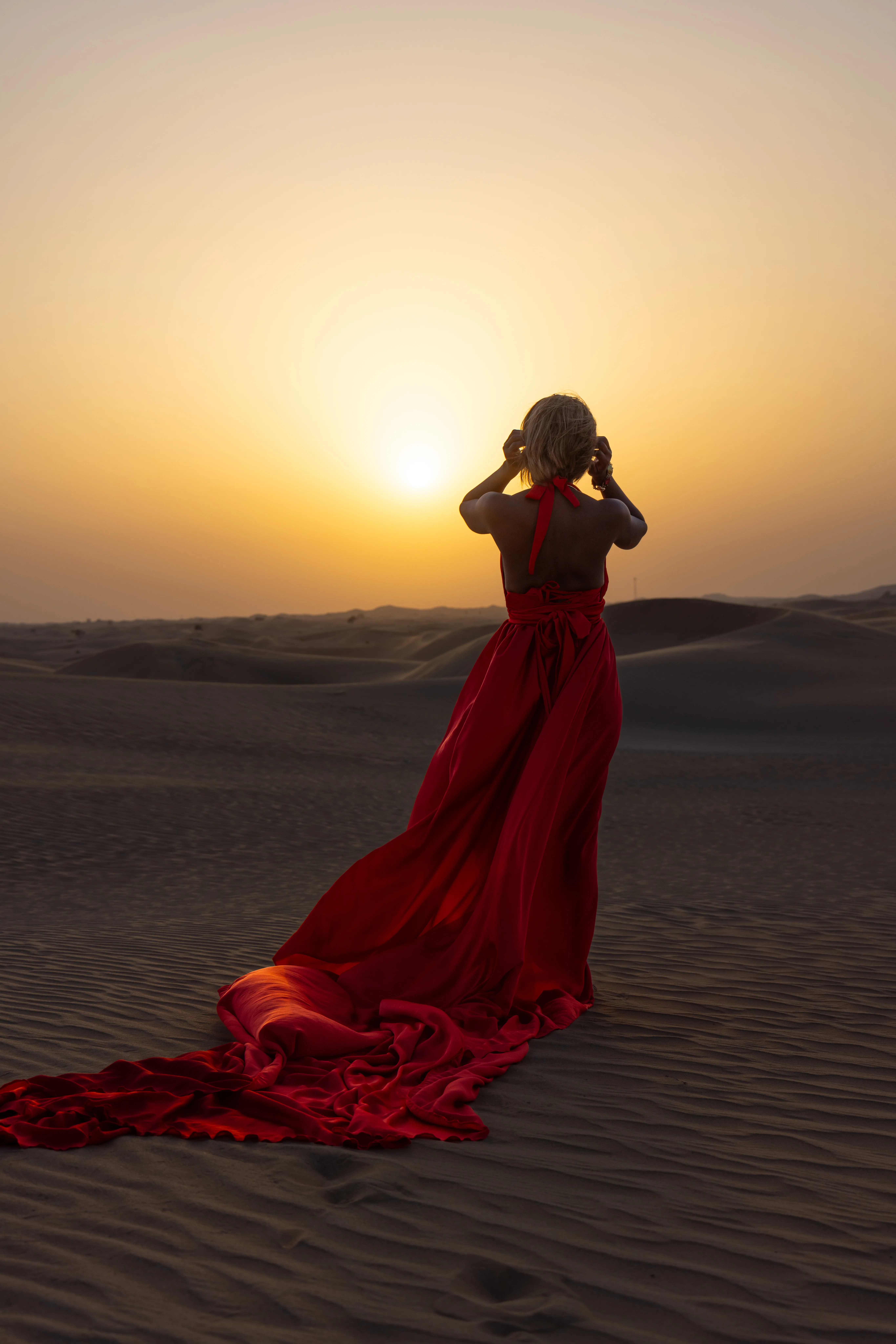 Red flying dress on dunes at sunset