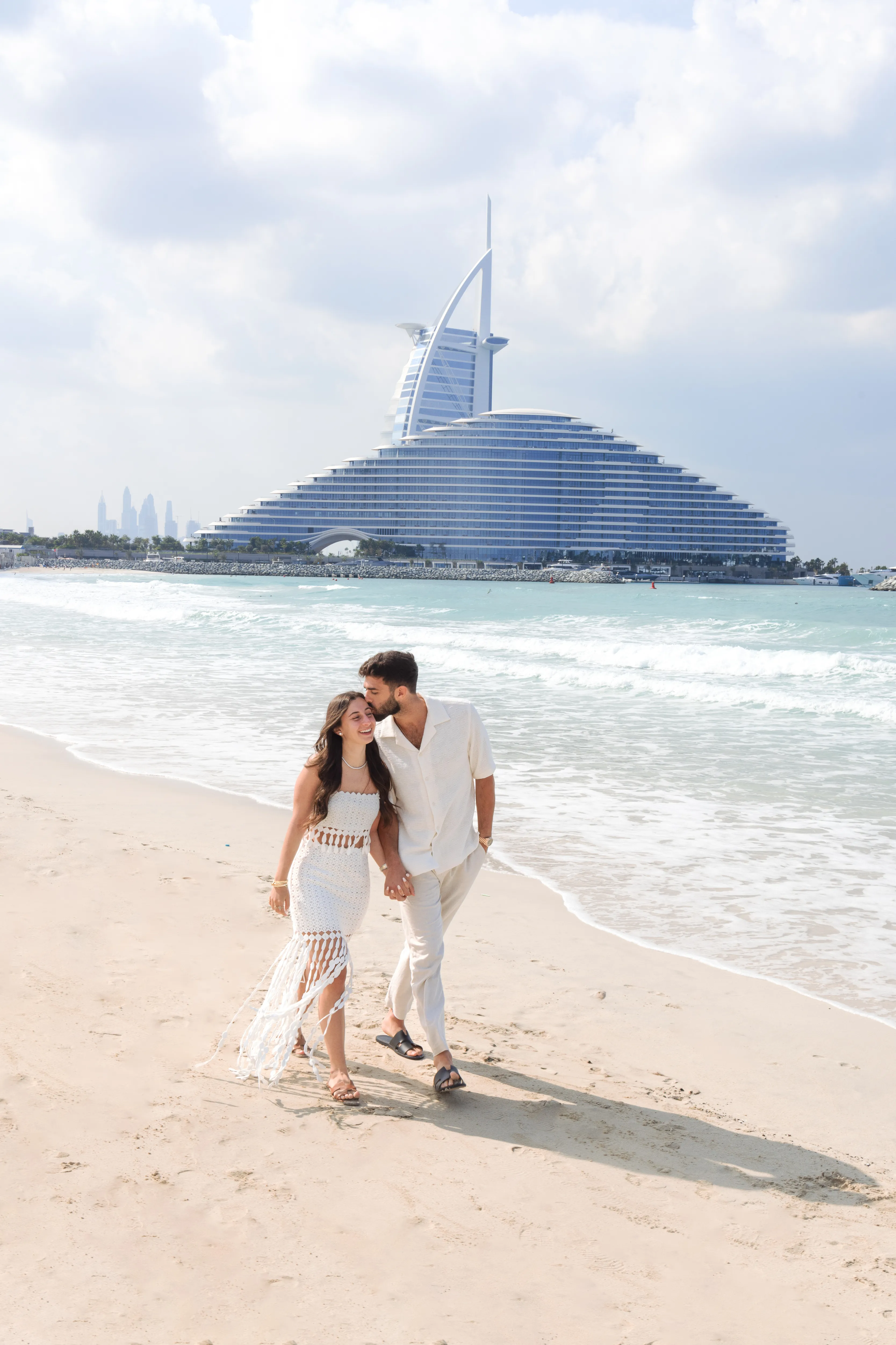 Couple walking at the shoreline, Jumeirah Beach Hotel behind