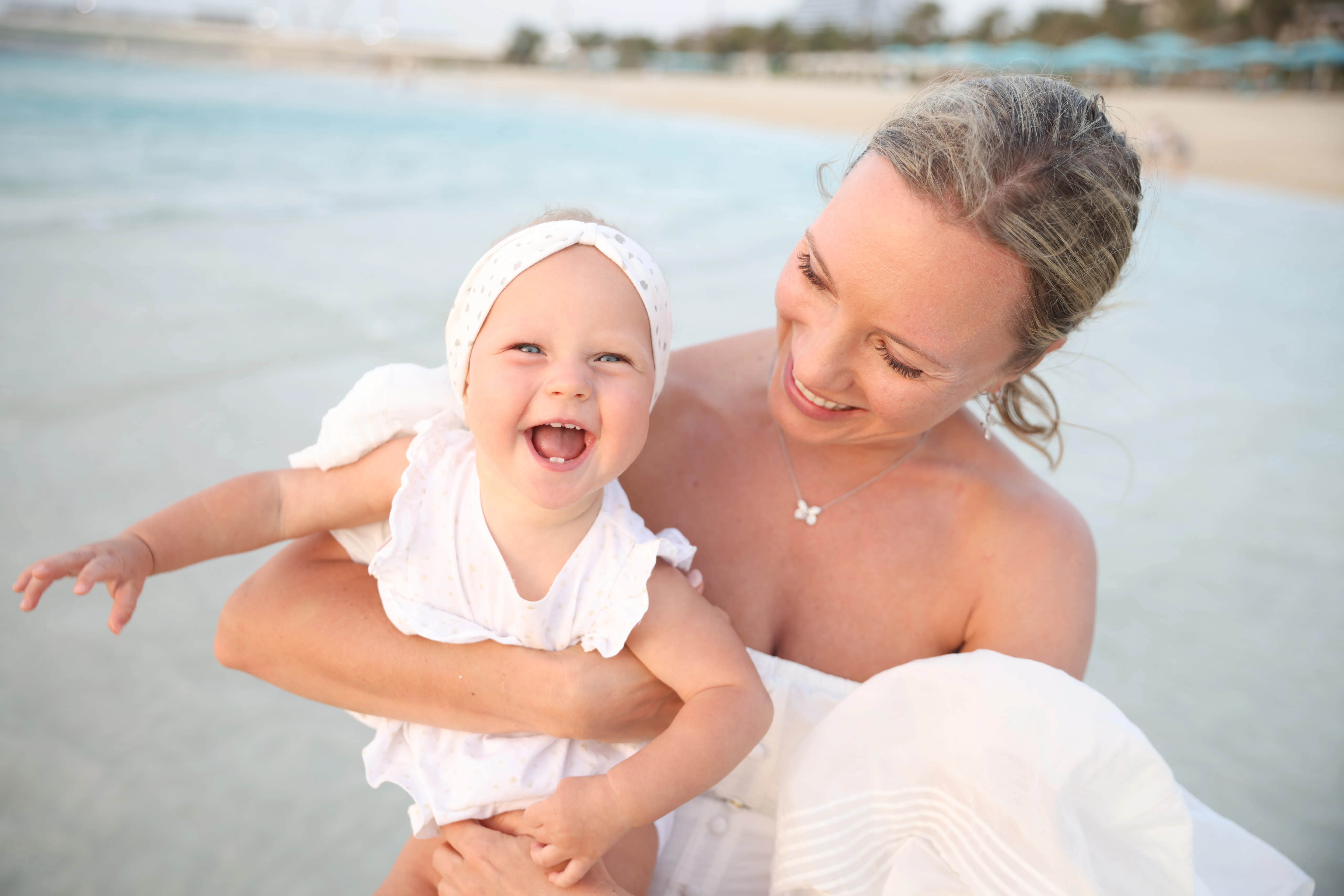 Mother and laughing baby, soft beach light