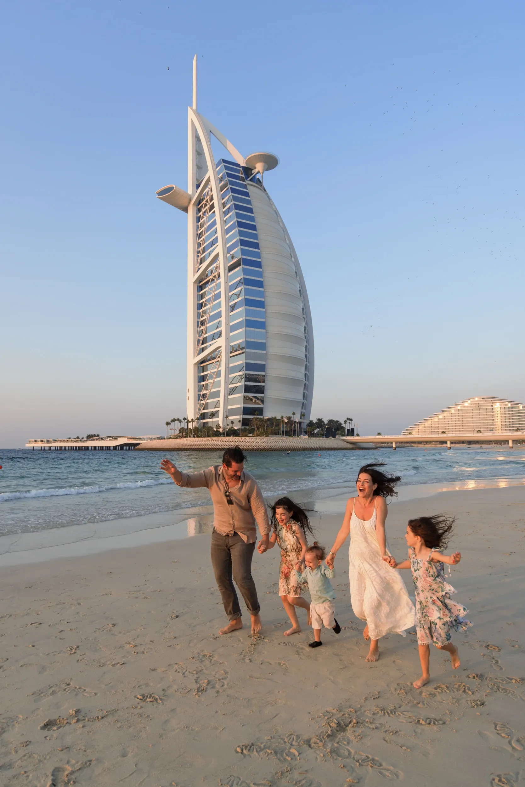A family walking on the beach with the Burj Al Arab behind.