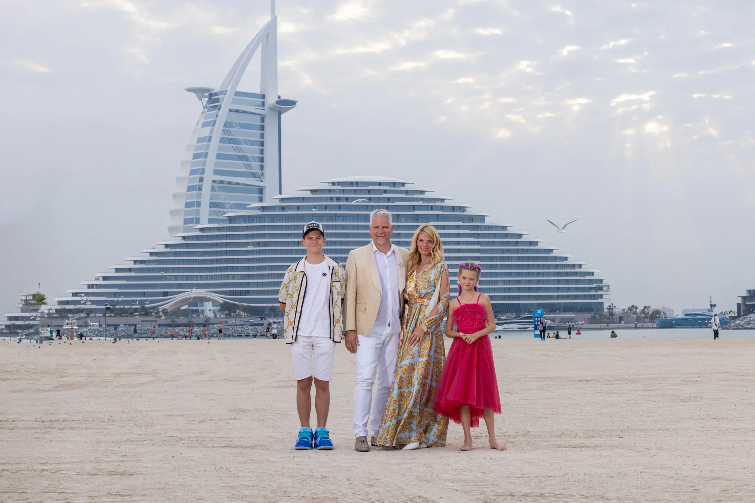 A family of four on a beach with the Burj Al Arab behind.