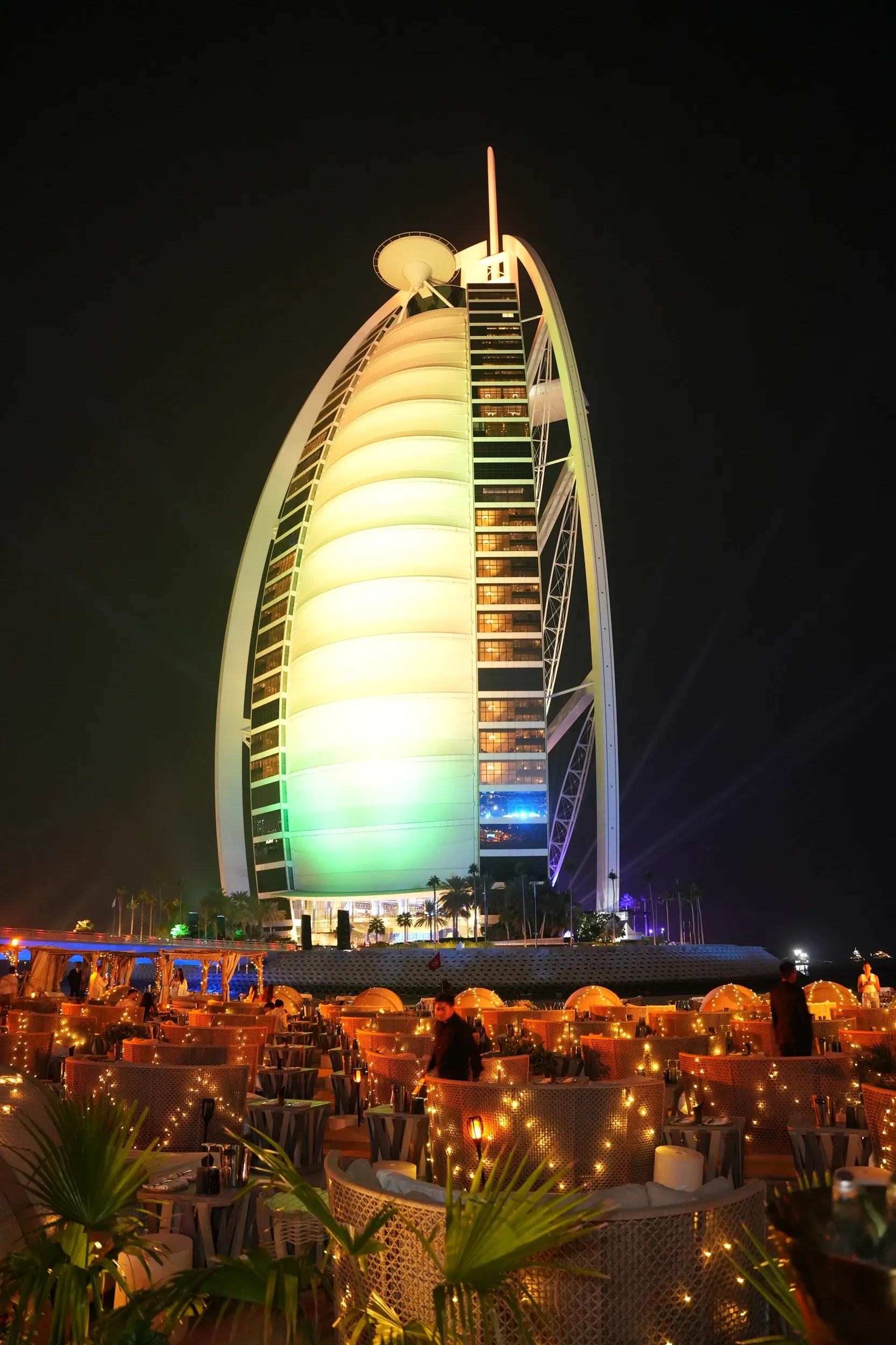 The Burj Al Arab illuminated in warm colours above an evening dining venue.