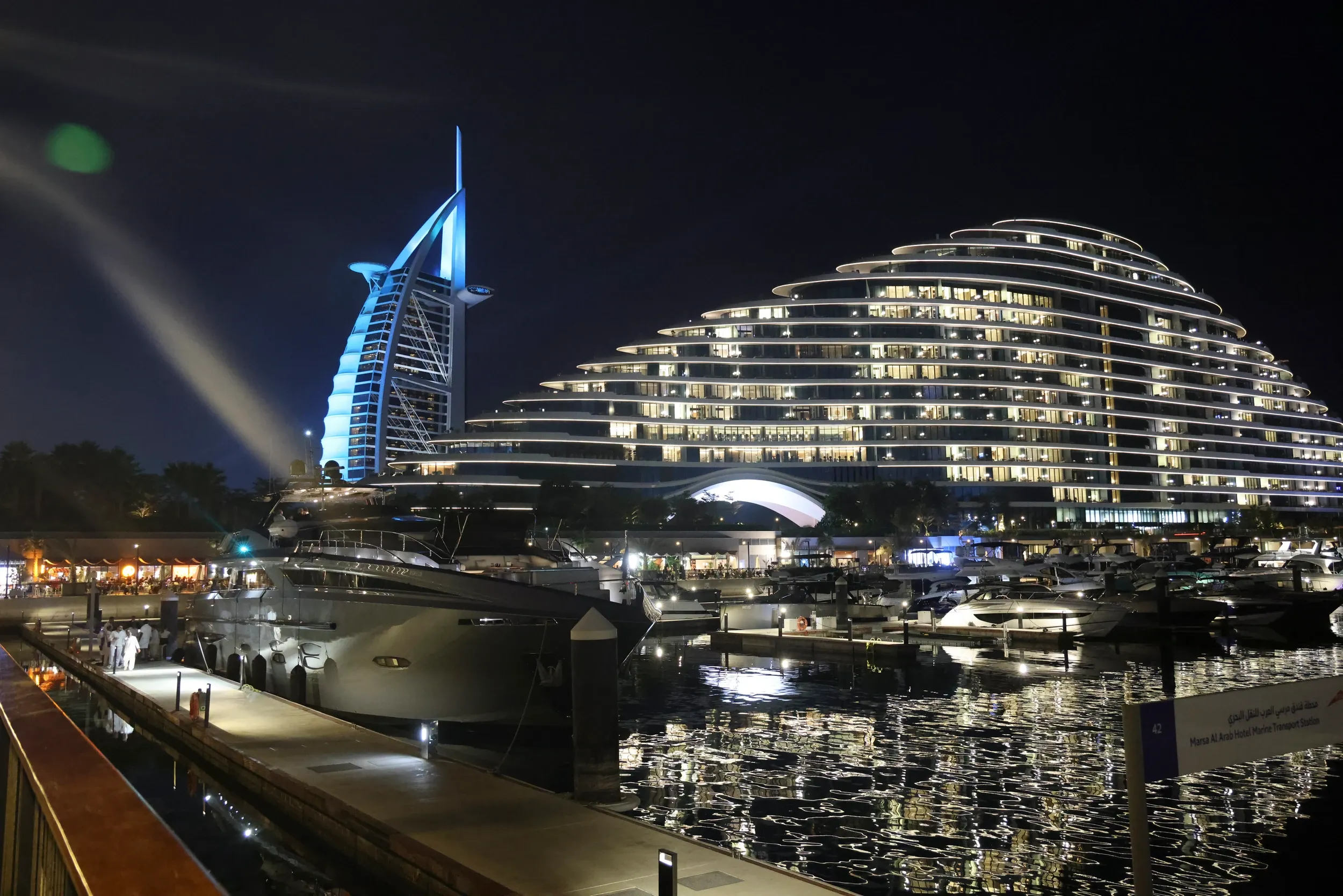 An illuminated waterfront hotel with moored yachts in Dubai