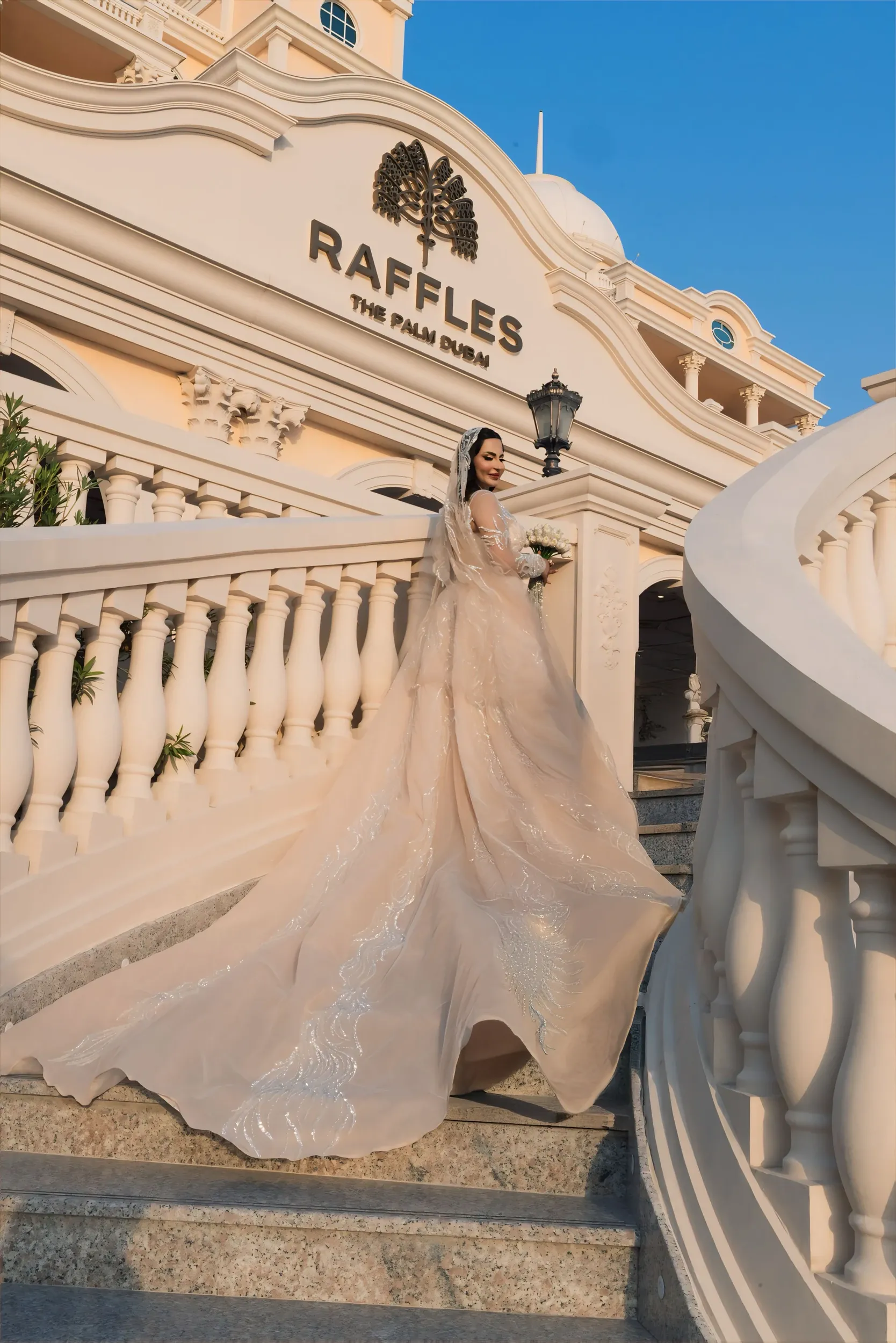 Bride with a long train on the curved staircase of Raffles The Palm, Dubai